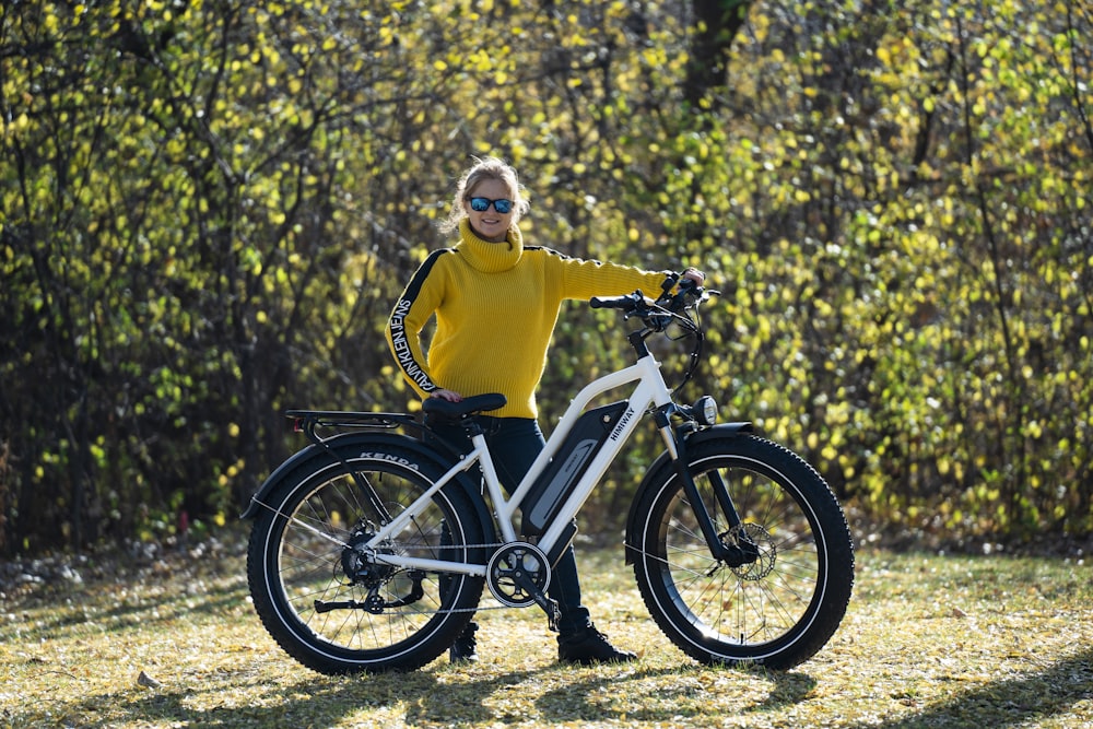 uomo in felpa con cappuccio gialla in sella a bicicletta bianca e nera