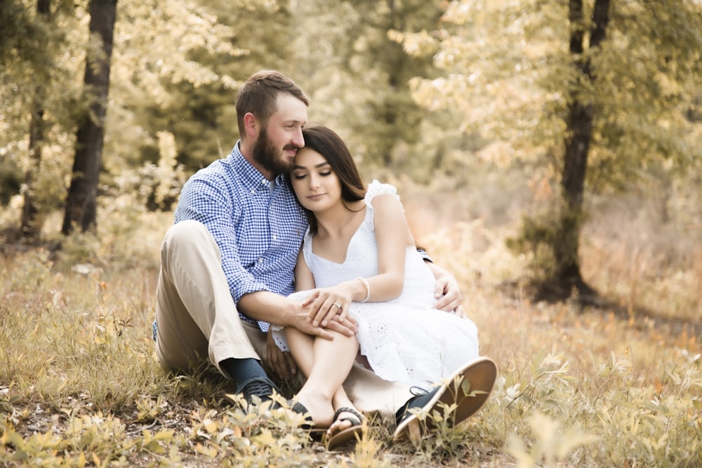 man and woman sitting on ground covered with dried leaves during daytime