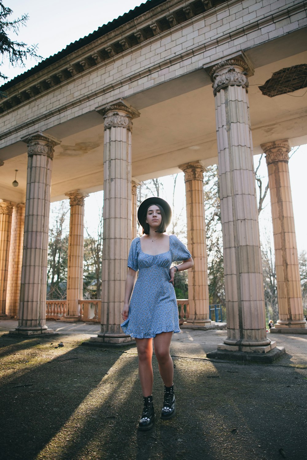 woman in blue dress standing in front of brown concrete pillar during daytime