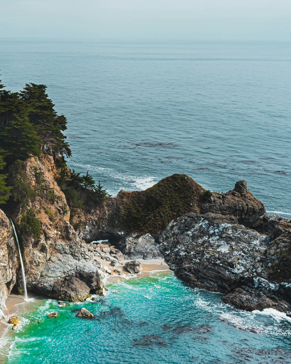 brown rocky mountain beside blue sea during daytime