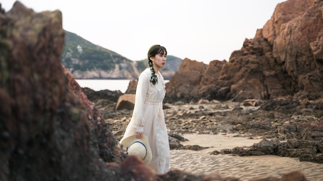 woman in white long sleeve dress standing on brown sand during daytime