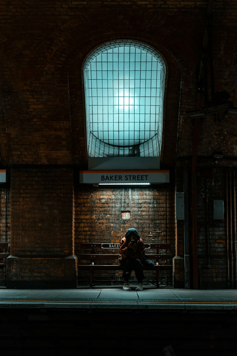 man in black jacket standing near brown brick building