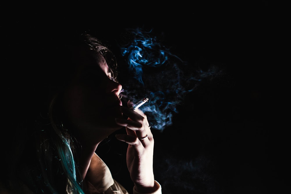 Frau raucht Zigarette auf schwarzem Hintergrund