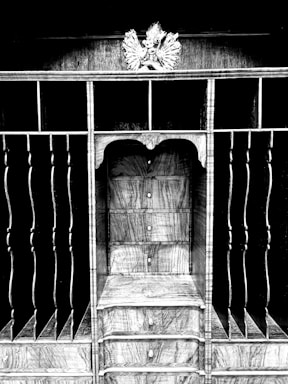 An intricately designed wooden structure featuring shelves and vertical slots with a decorative element on top. The central section includes multiple drawers with round knobs, showcasing a wood grain pattern.