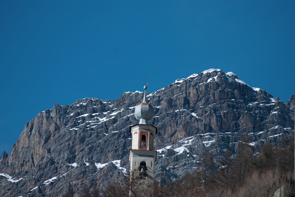 white and brown concrete building near rocky mountain under blue sky during daytime