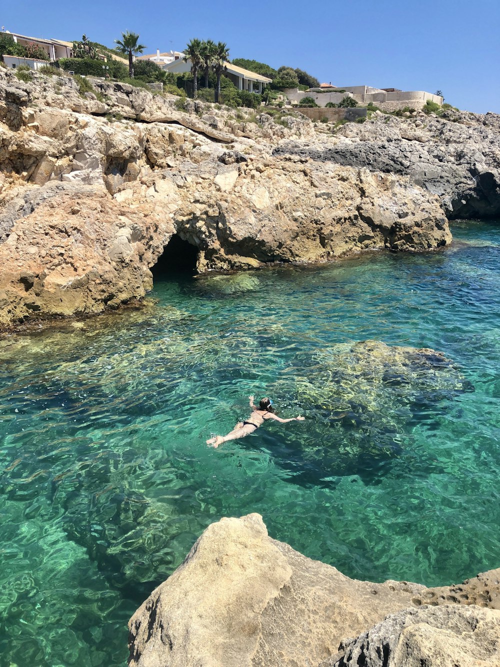 woman in blue bikini swimming on blue water during daytime