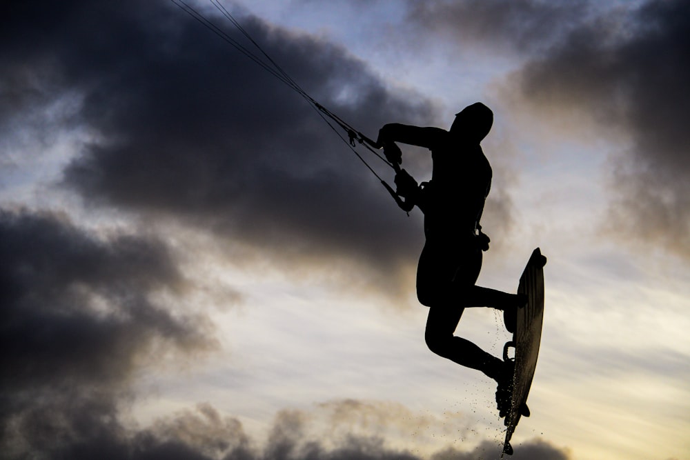 silhouette of man riding on skateboard under cloudy sky during daytime