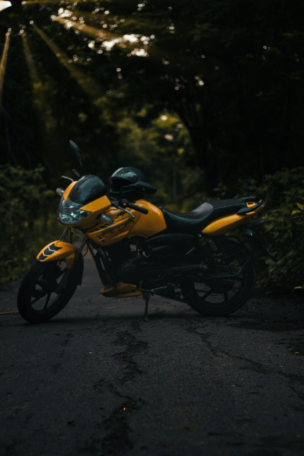 yellow and black motorcycle parked on gray asphalt road during daytime