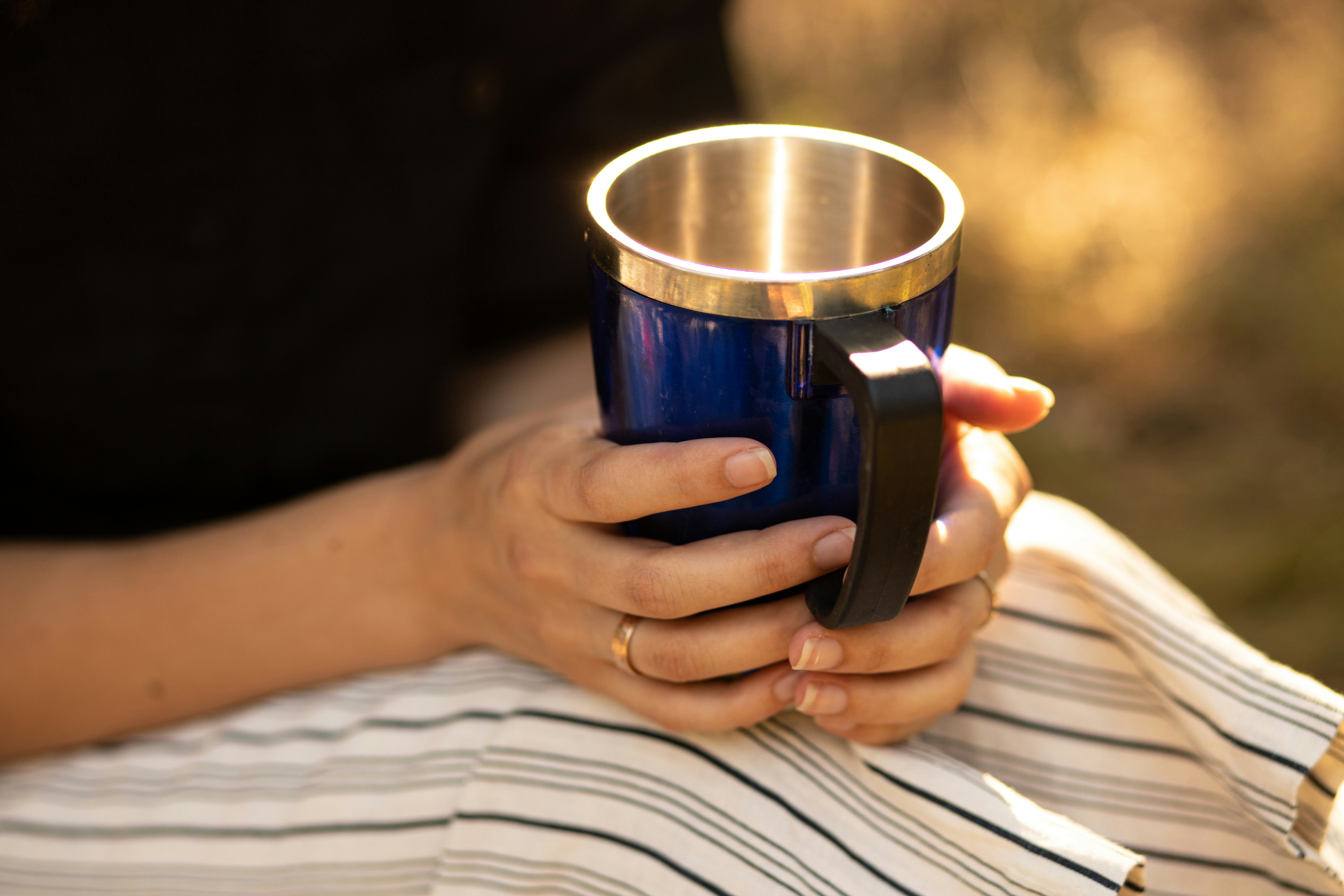 person holding blue and silver mug