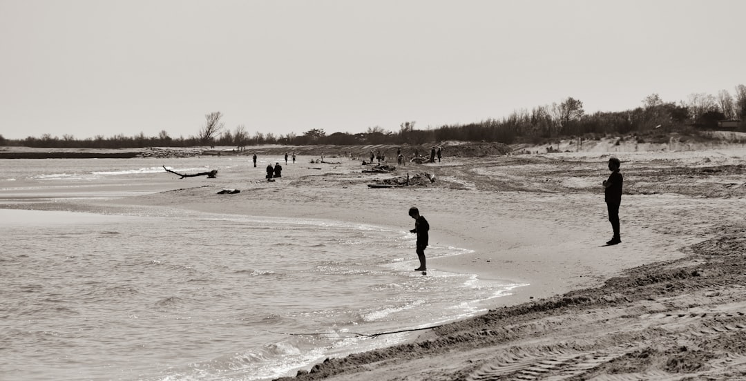 man in black jacket walking on white sand beach during daytime