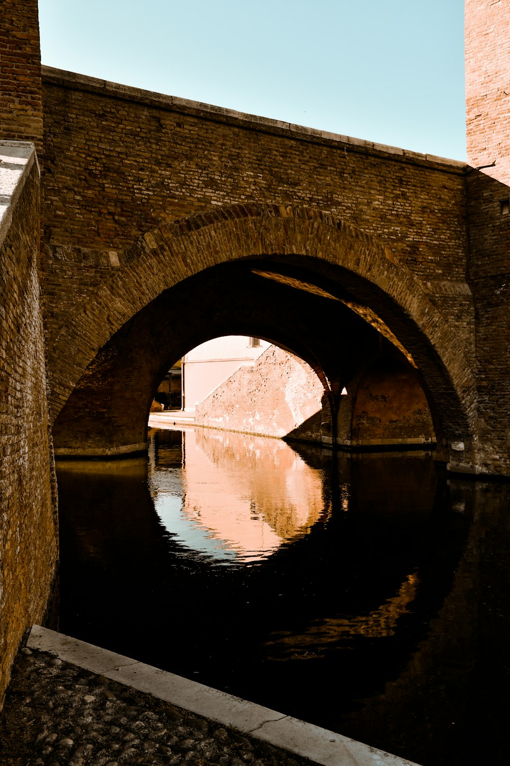 昼間の川に架かる茶色のコンクリート橋