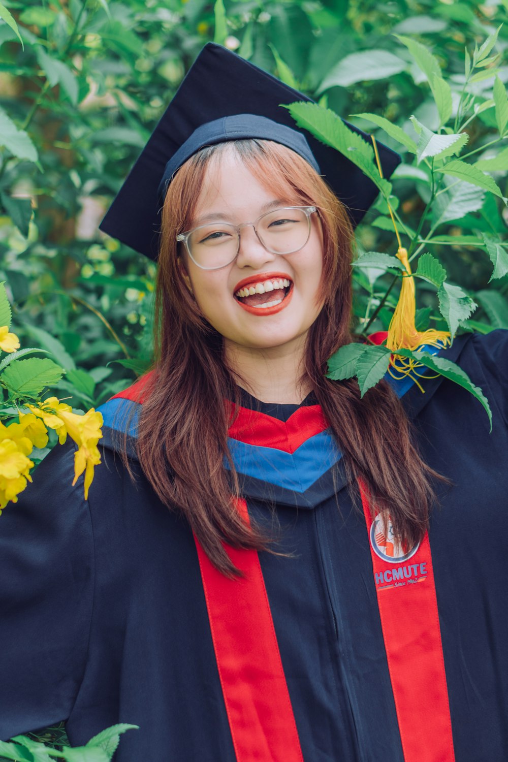 smiling woman in black academic dress and red scarf