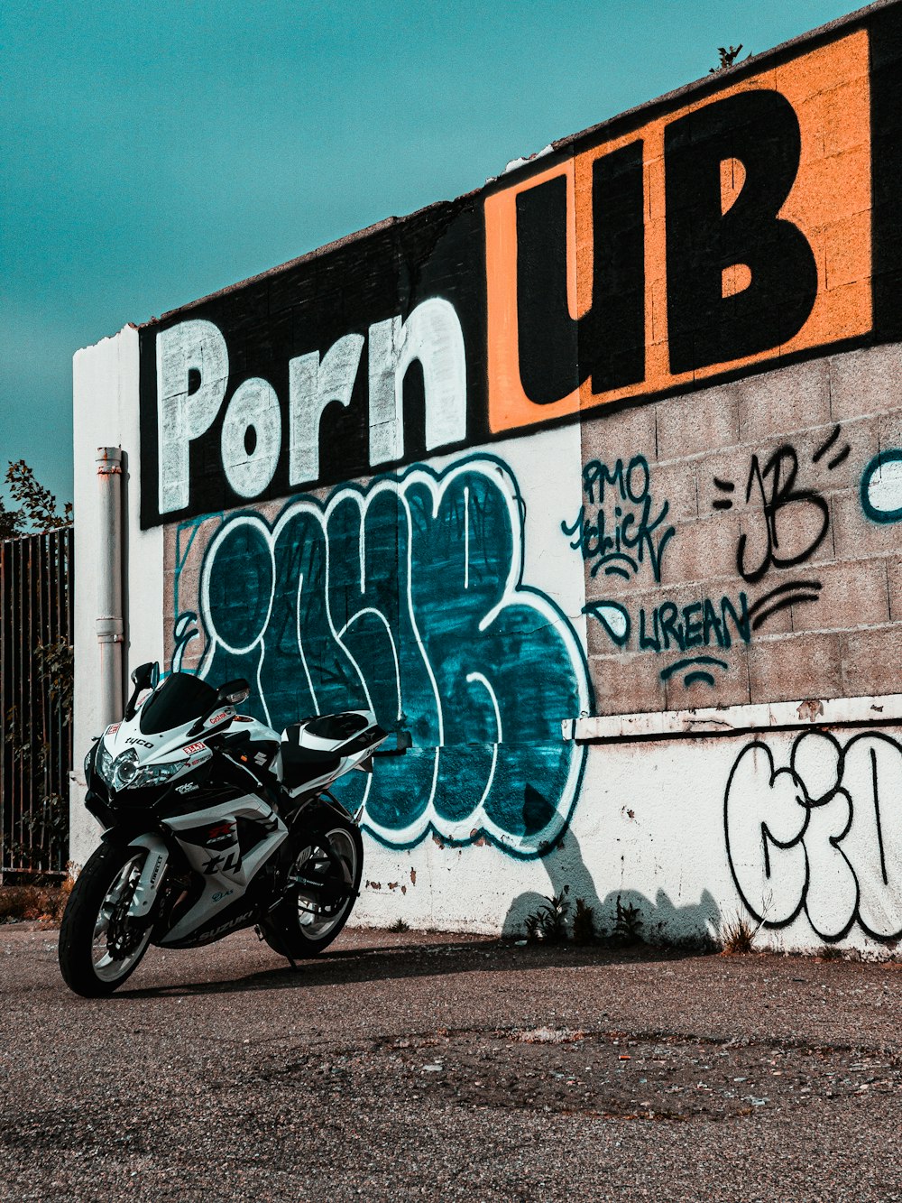 black motorcycle parked beside wall with graffiti