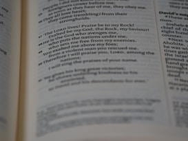A close-up view of a book open to a specific page with text in a serif font. The focus is on a passage with the words 'The LORD lives! Praise be to my Rock!'. The image captures part of a religious or spiritual book, possibly a Bible.