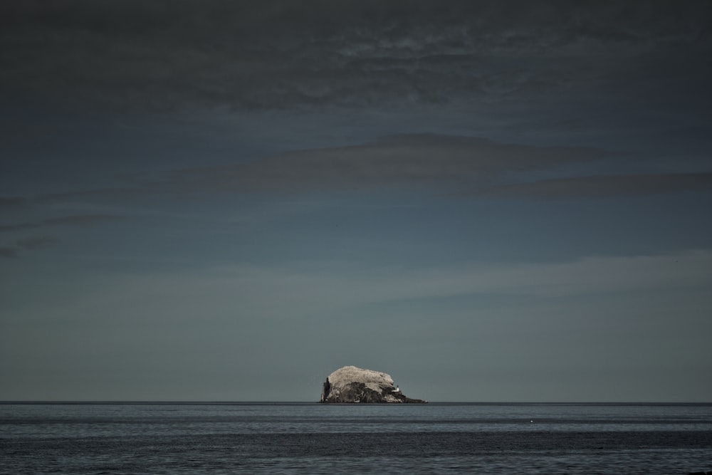 brown rock formation on sea under blue sky during daytime