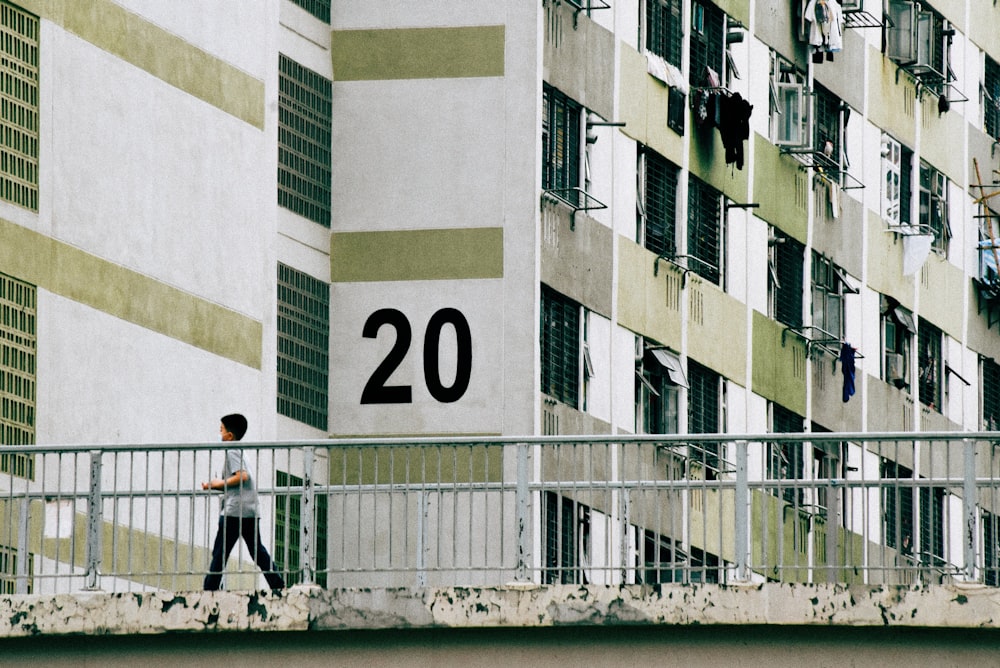 man in black jacket walking on sidewalk near white concrete building during daytime