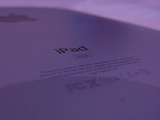 The close-up image focuses on the back of an iPad with the storage capacity clearly marked as 16GB. The branding and regulatory information are visible, set against a backdrop of subtle lighting, giving a muted purple hue.