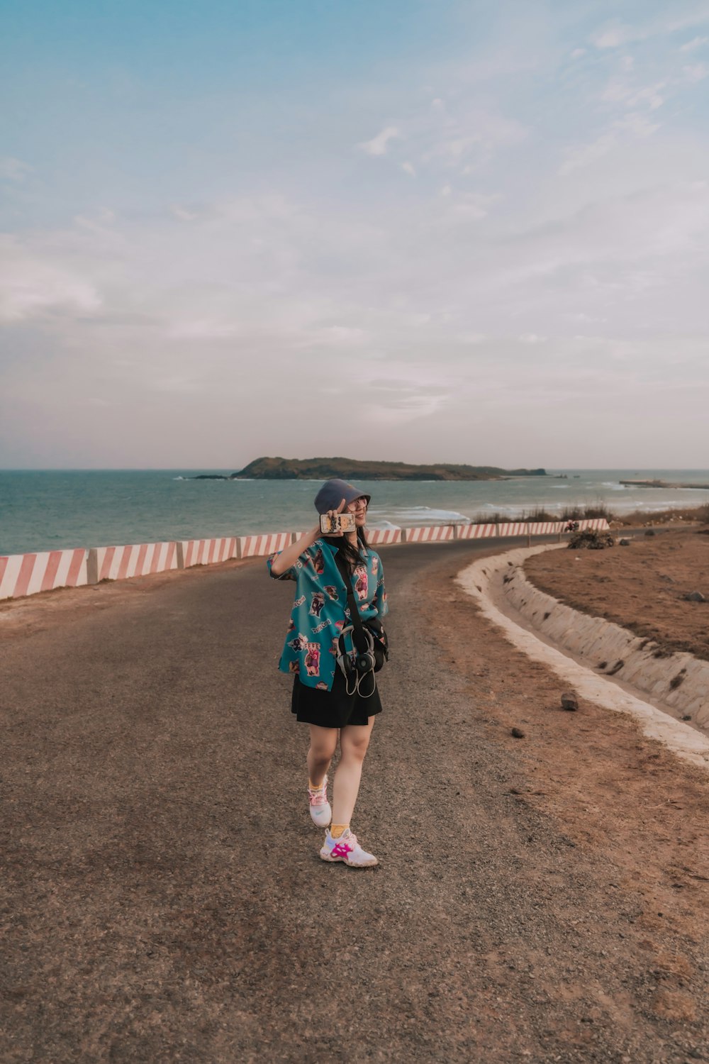 woman in blue and red dress standing on brown sand near body of water during daytime