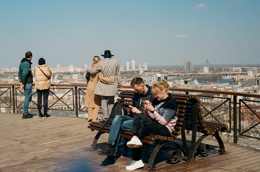 man and woman sitting on brown wooden bench during daytime