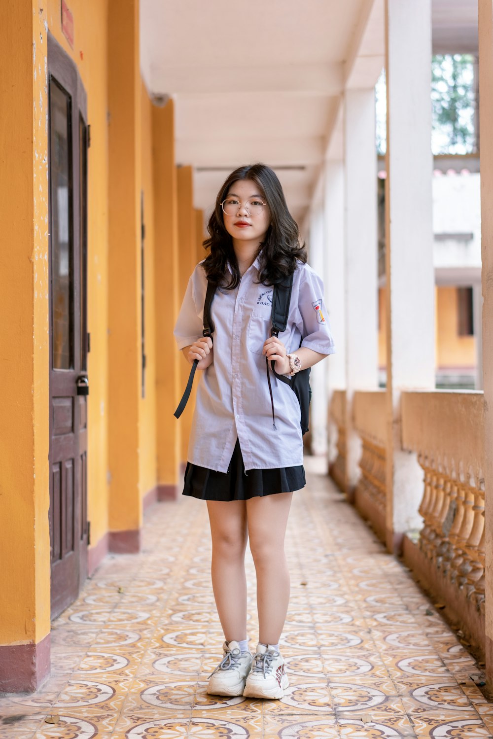 woman in white coat standing on sidewalk during daytime