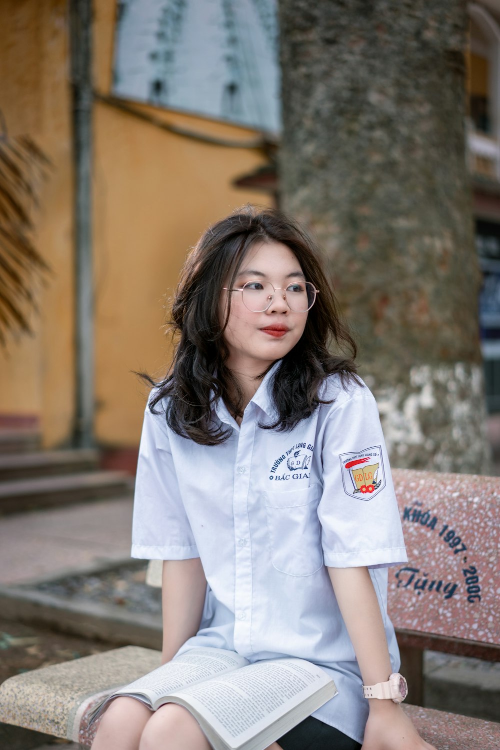 girl in white button up shirt standing near brown concrete wall during daytime