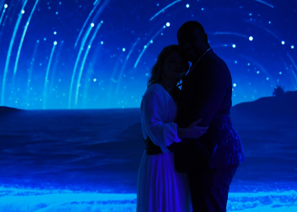 hombre y mujer besándose bajo el cielo azul durante la noche