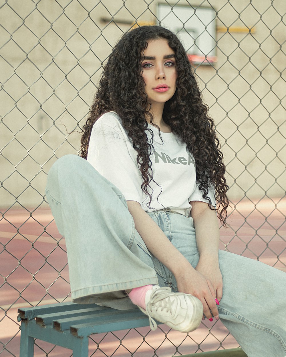 Femme en chemise blanche et short en jean bleu assise sur un banc en béton bleu