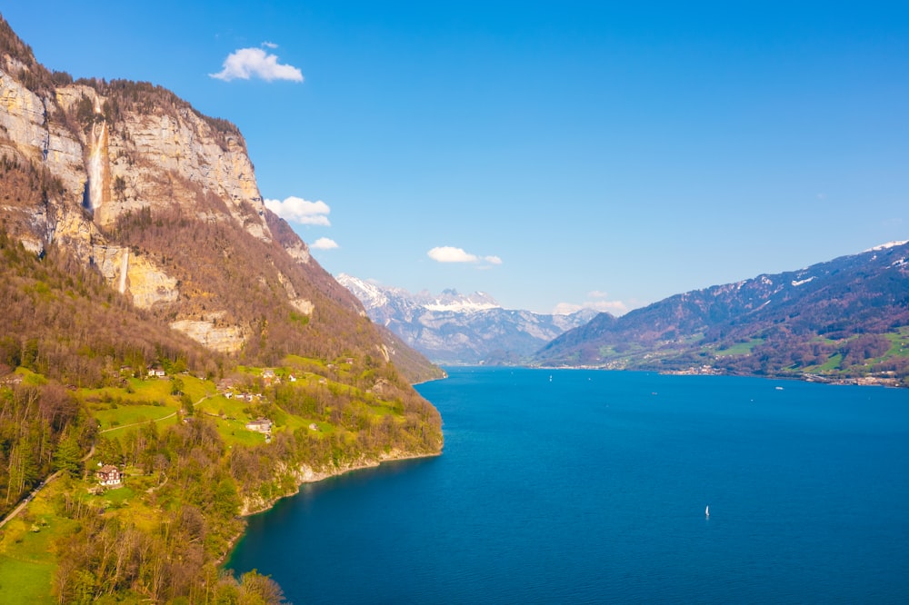 green and brown mountain beside blue sea under blue sky during daytime