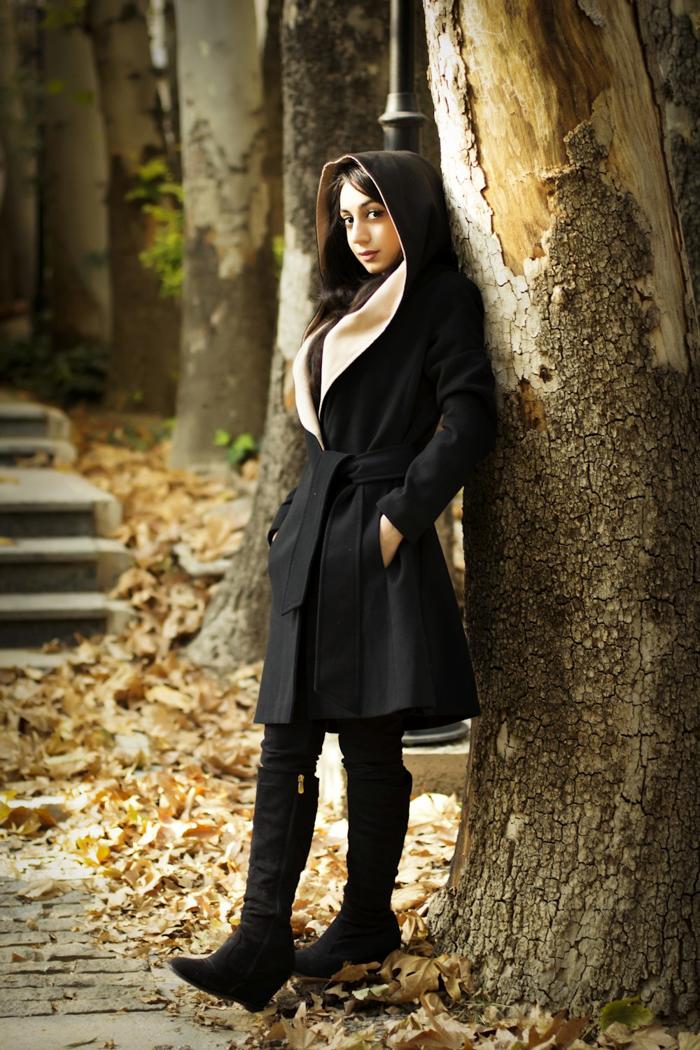 woman in black coat standing beside tree
