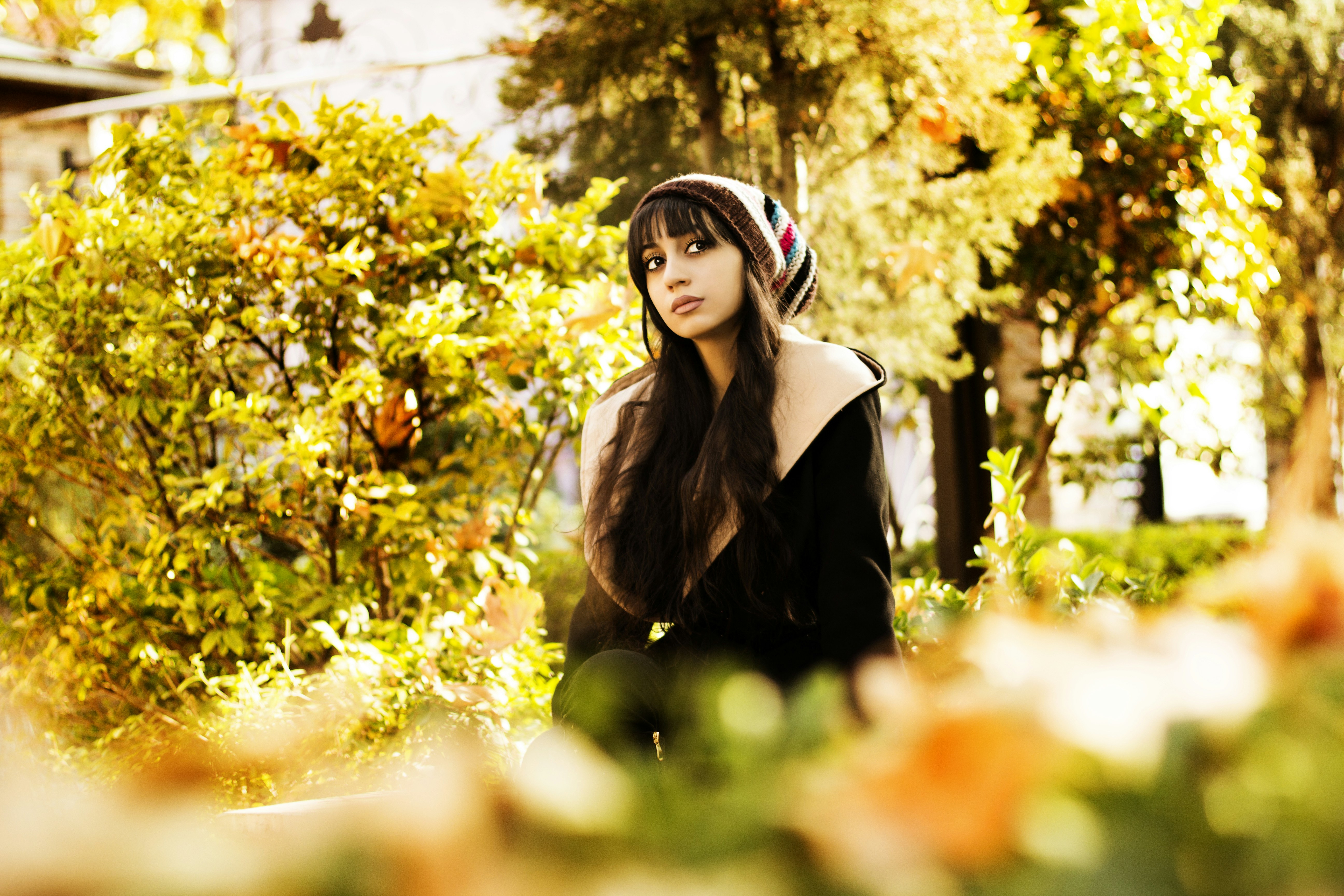 woman in black leather jacket standing near green tree during daytime
