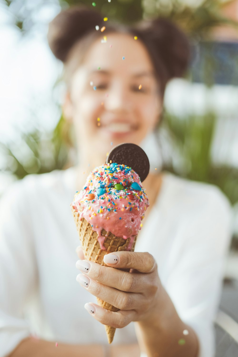 person holding ice cream cone with sprinkles
