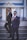 Two men in formal suits stand confidently on steps in front of an elegant building with classical architecture. Both wear sunglasses and have their hands in their pockets, exuding a sense of style and sophistication. The building features large windows and decorative elements with blue and gold accents.