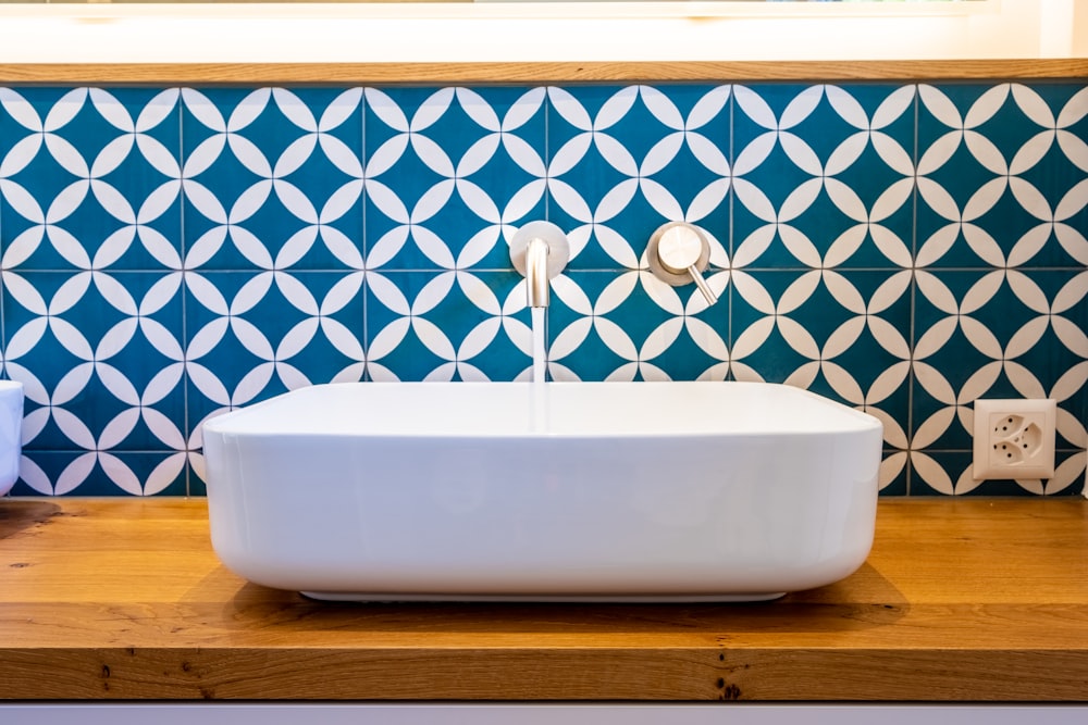 white ceramic bathtub with blue and white wall tiles