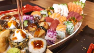 Variety of nigiri and sashimi arranged on a rustic wooden platter.