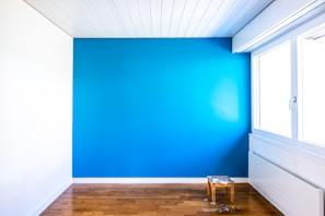 Bright workspace with a large window, light wood furniture, and a calming blue accent wall