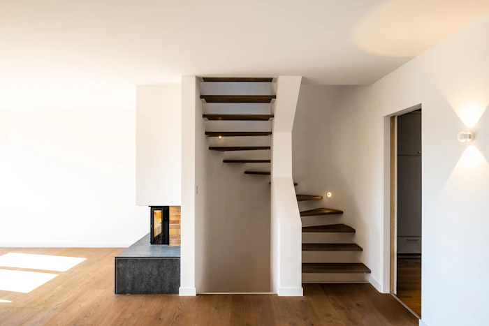 Escalera de madera flotante y paredes blancas en una casa reformada