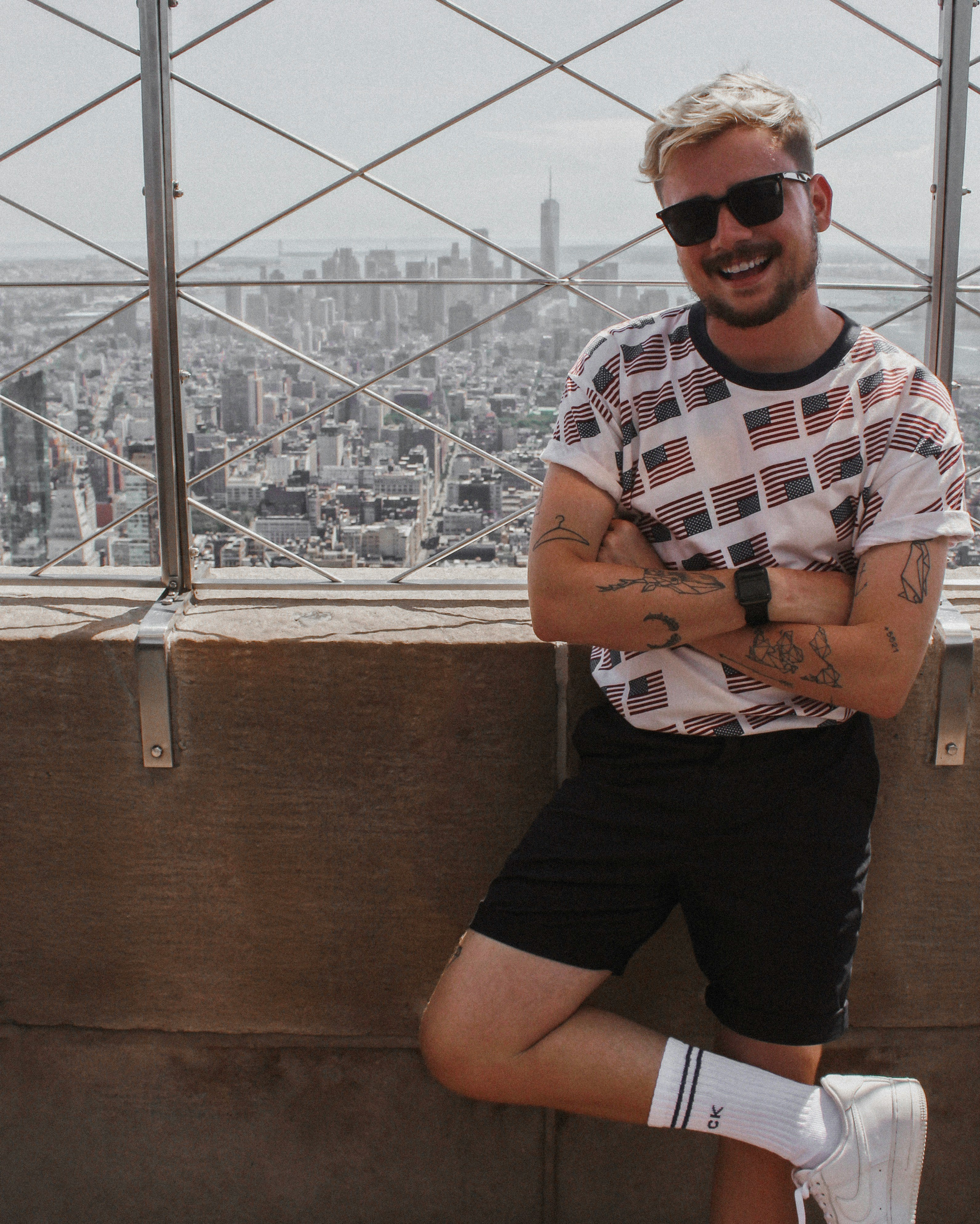 man in white and black striped crew neck t-shirt and black shorts sitting on brown