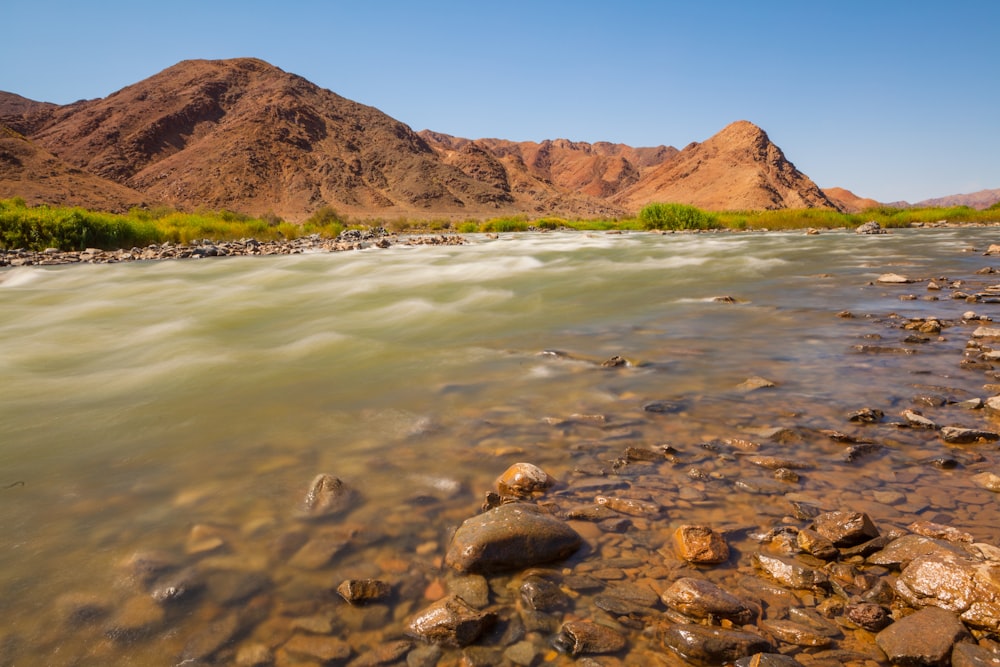 brown mountain beside body of water during daytime