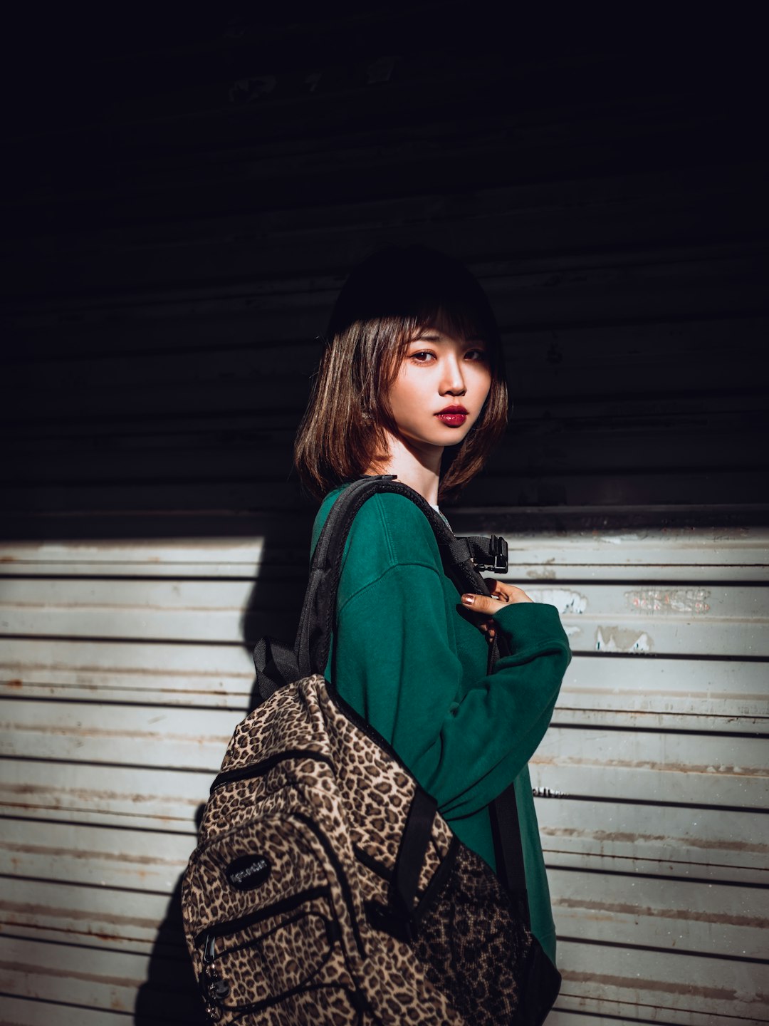 woman in black and brown long sleeve shirt standing beside gray roll up door