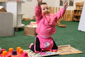 A joyful child engaging with colorful educational tools under supervision.