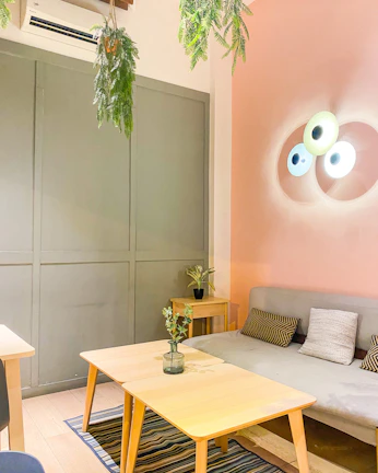 Softly lit living room with warm beige walls, minimalist shelves, and a small potted plant adding a touch of green.