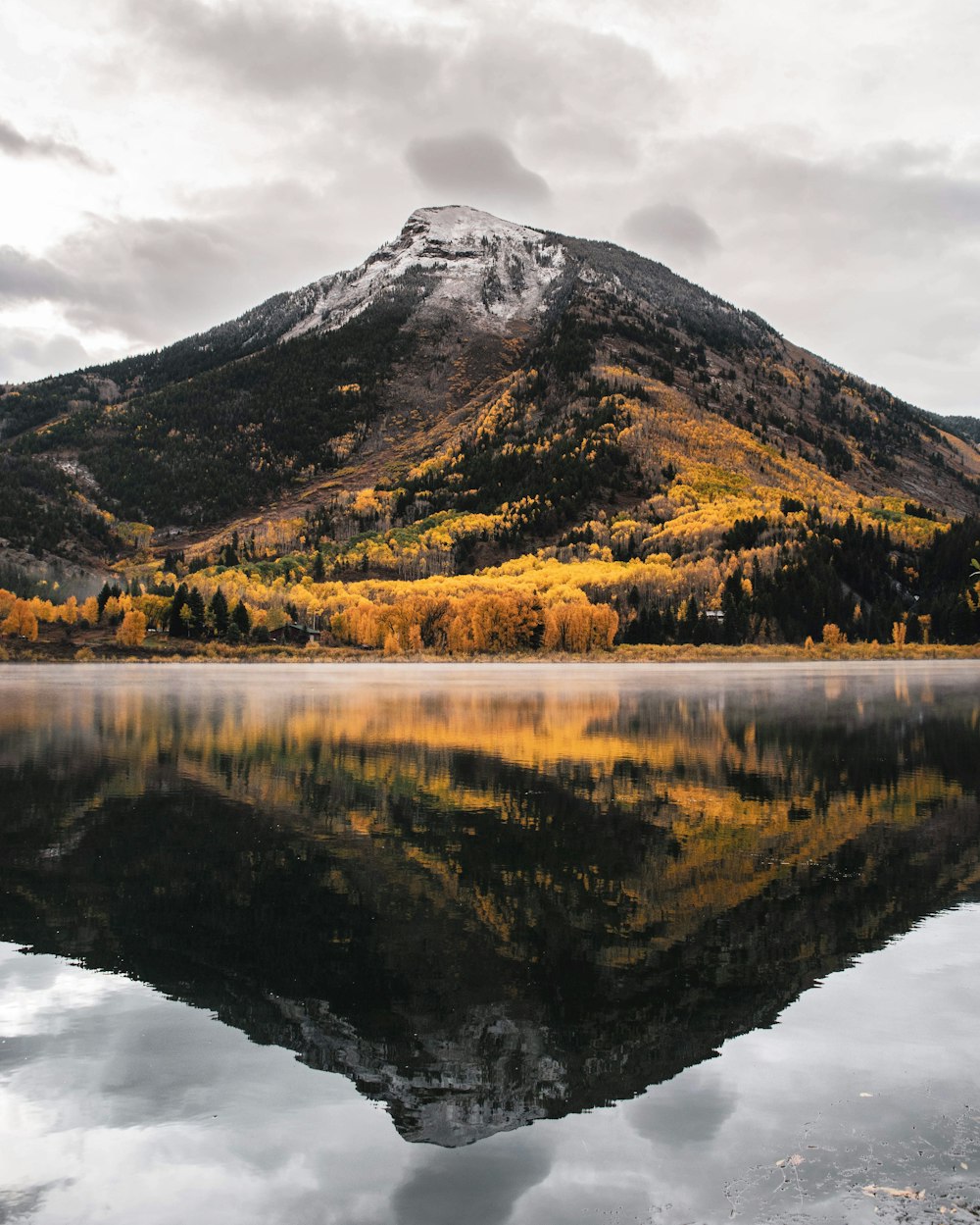 green and brown mountain beside lake under cloudy sky during daytime