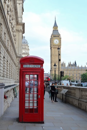 red telephone booth near brown concrete building during daytime