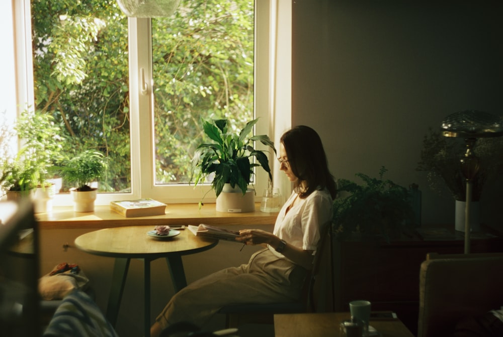 woman in white dress shirt sitting on chair near window during daytime