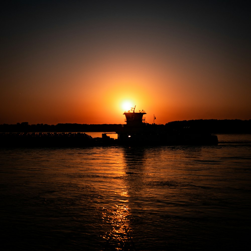 silhouette of building near body of water during sunset