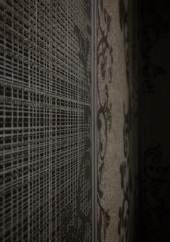 A textured surface features intricate, abstract patterns with fine lines and swirling designs. The wall presents a blend of geometric and ornamental motifs that create a sense of depth and complexity.