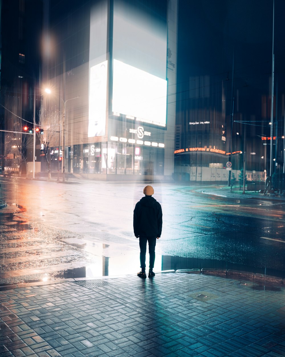 man in black coat walking on street during night time
