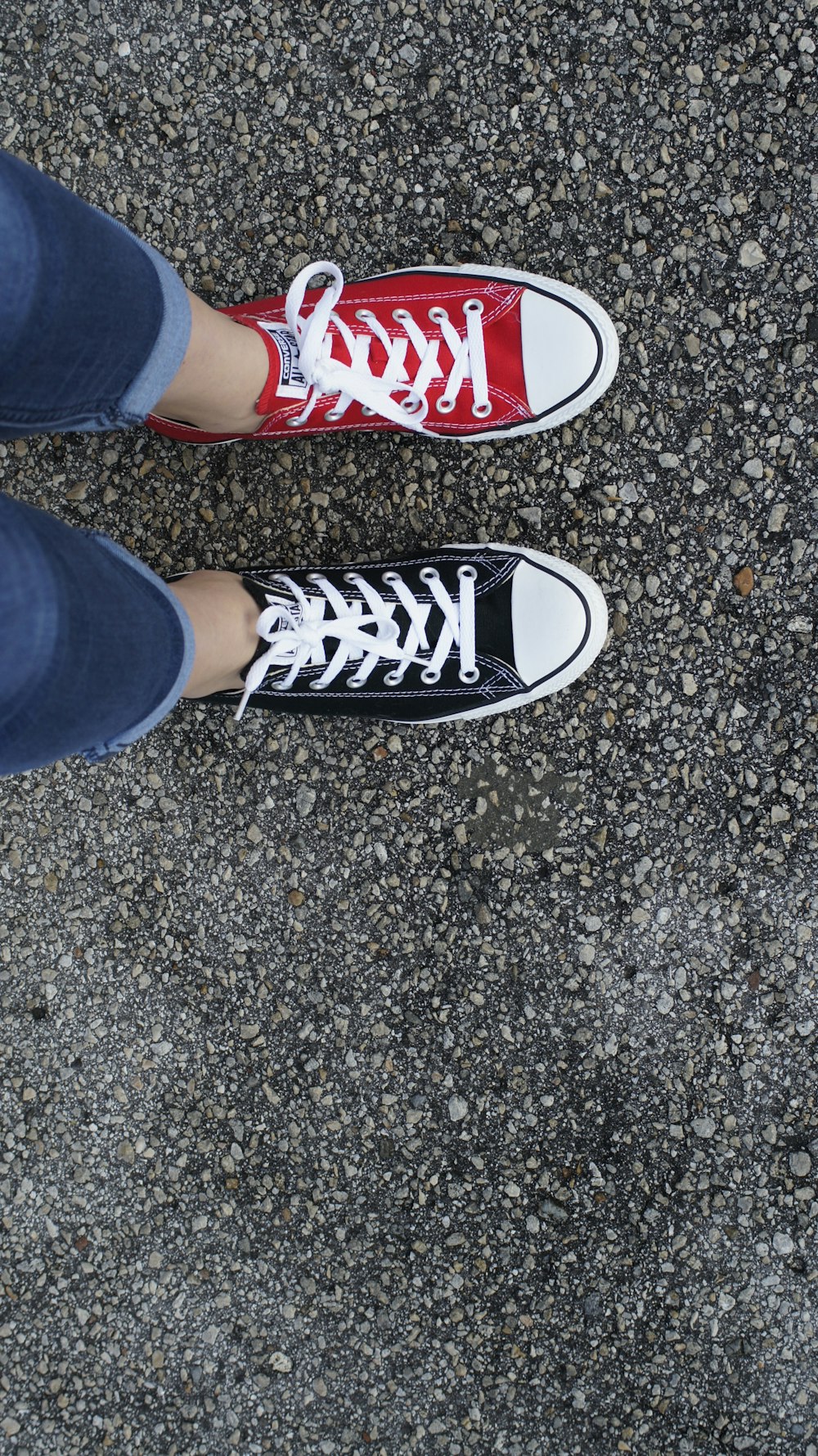 Persona con jeans de mezclilla azules y zapatillas altas Converse All Star en blanco y negro