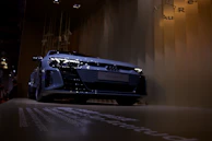 Side profile of the axv tm-fs parked against a sleek silver wall, highlighting its minimalist design and sharp lines.