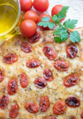 Artisanal focaccia topped with fresh herbs and olive oil, photographed with soft natural light.